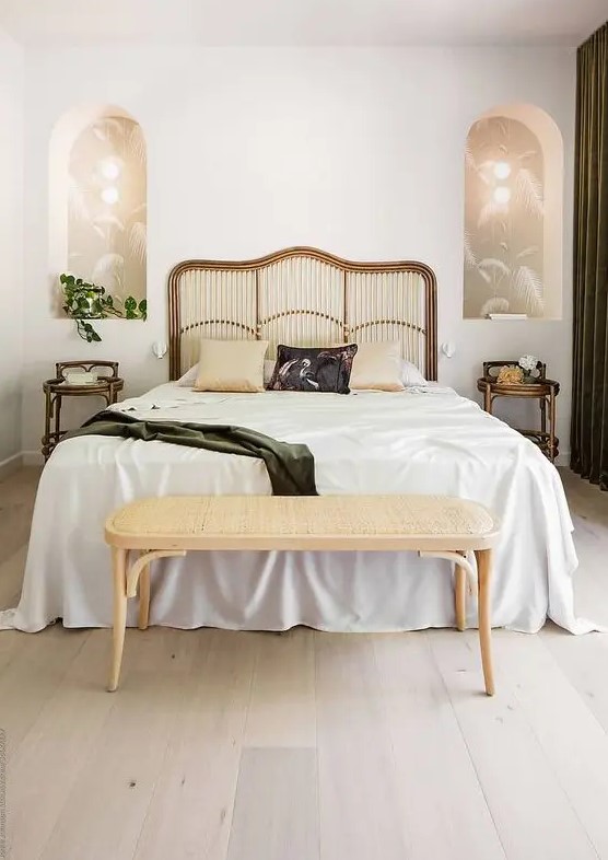 a beautiful art deco bedroom with a bed with a catchy headboard, arched niches with lights inside and rattan nightstands