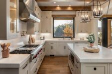 a beautiful modern farmhouse kitchen with dove grey cabinets, white stone countertops, wooden beams, pendant lamps