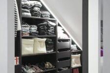 a black and white attic closet with open storage compartments, drawers and shoe stands plus built-in lights