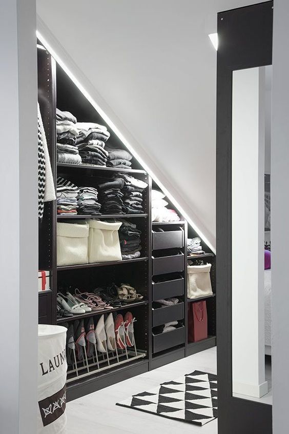 a black and white attic closet with open storage compartments, drawers and shoe stands plus built-in lights