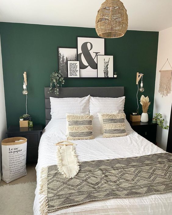 a boho neutral bedroom with a forest green accent wall, a grey bed and neutral bedding, a macrame, a gallery wall, a pendant lamp