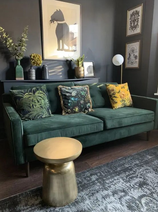 a bold living room with graphite grey walls, a dark green sofa and printed pillows, a coffee table and some artwork