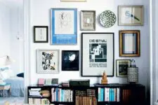 a bright eclectic free form gallery wall over a black storage unit are a cool combo for a vintage or retro space