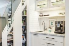a built-in kitchen under the stairs with lights, tall drawers to store food and other stuff as in a pantry