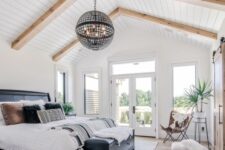a catchy modern farmhouse bedroom with a shiplap ceilign, a black bed with contrasting bedding, a black dresser and a sphere lamp