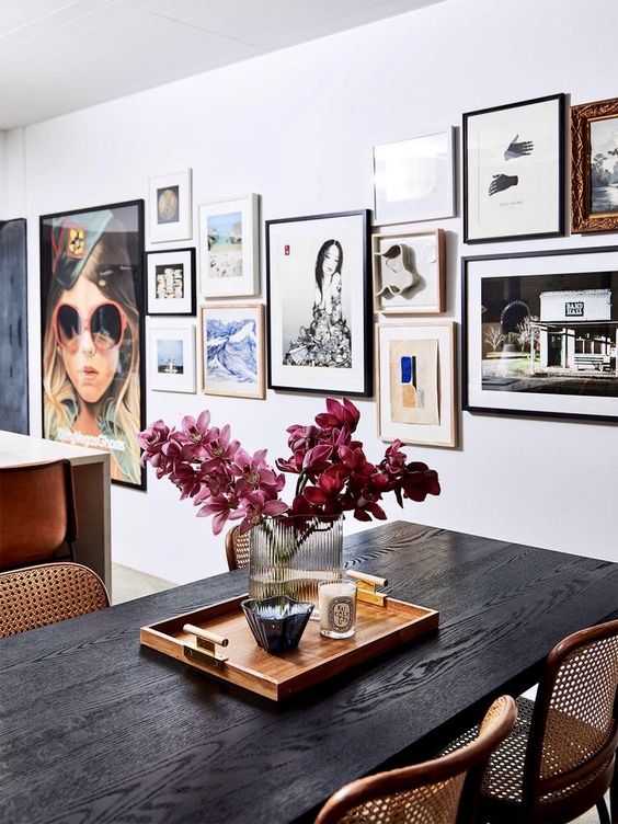 a catchy space with a dark-stained table and woven chairs, a bright gallery wall with mismatching frames and mismatching art