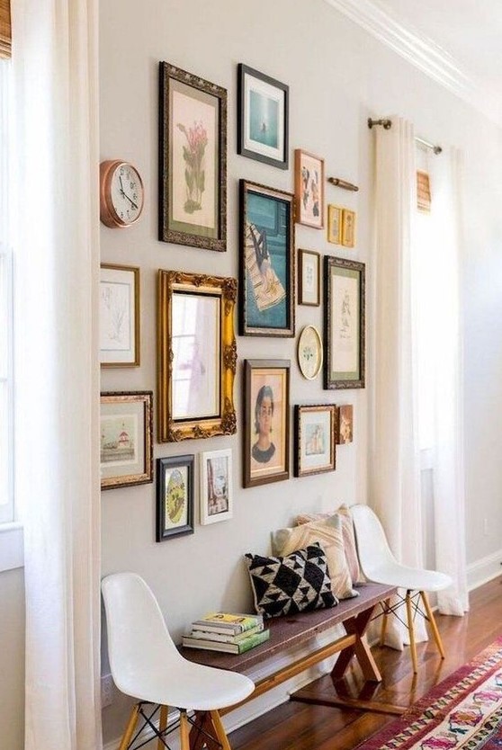 a chic free form gallery wall with vintage frames and colorful art of various kinds plus a clock is catchy