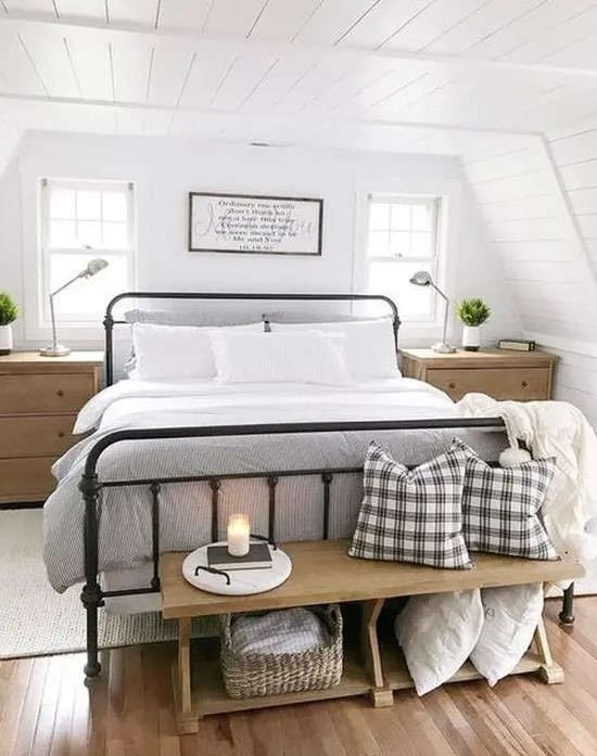 a chic modern farmhouse bedroom with white walls, a forged bed, wooden furniture and touches of plaid here and there