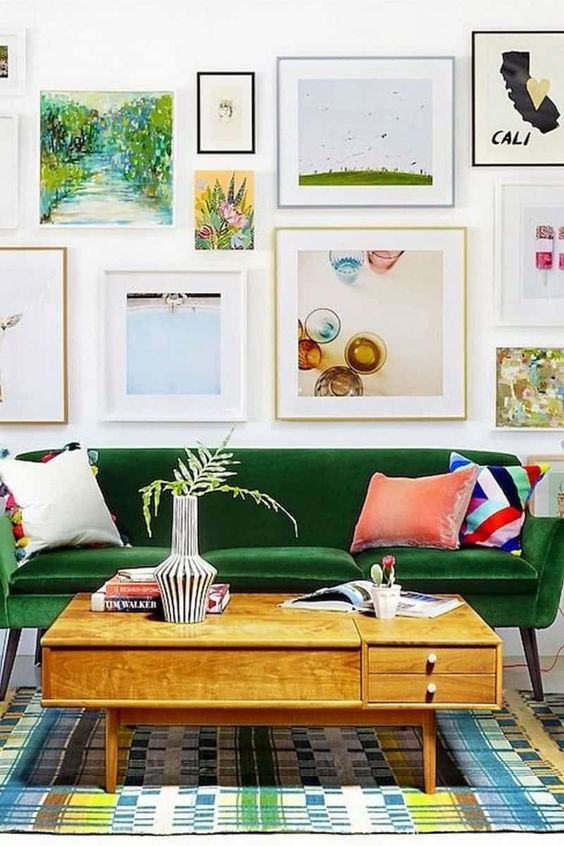a colorful living room with a green sofa, a stained coffee table, a printed rug, a free form gallery wall