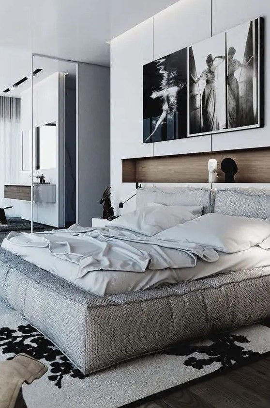 a contemporary bedroom with a soft bed and neutral bedding, a niche used for decor and some artwork plus a graphic rug