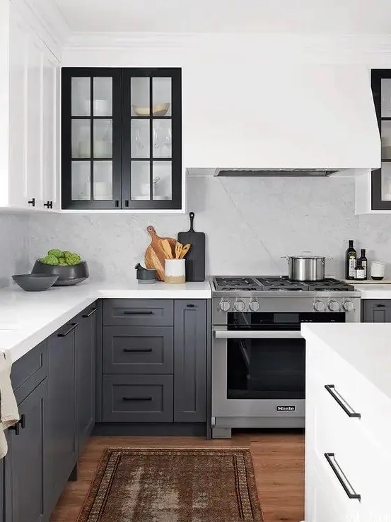 a contrasting kitchen with white upper cabinets and charcoal grey ones, black glass frame cabinets and a white backsplash and countertops
