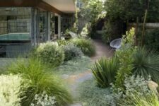 a cool and textural side yard with a wooden deck and irregular stone paths, lots of greenery and grasses for a catchy look
