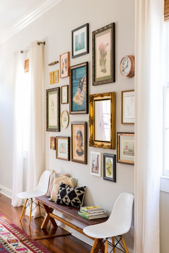a cool space with a stained bench and white chairs, a vintage free form gallery wall with mismatching frames