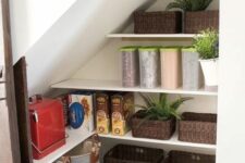 a cool staircase pantry with a sliding barn door, plastic containers, fabric and wicker baskets, potted greenery