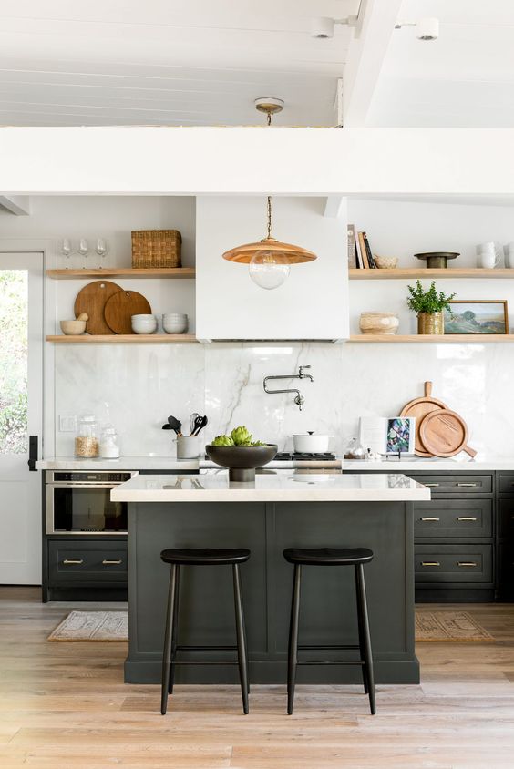 a cozy black and white farmhouse kitchen with shaker cabinets, a kitchen island, stained shelves instead of upper cabinets and a brass pendant lamp