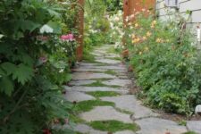 a cozy cottage-style side yard with an irregular stone path, greenery and blooms is a cool and lovely nook