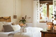 a farmhouse bedroom with wooden beams on the ceiling, wooden furniture, neutral bedding and candle lanterns is very cozy