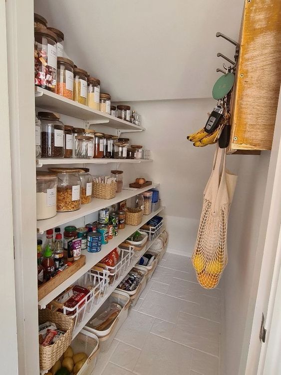 a functional staircase pantry with open shelves, cubbies and baskets, a wooden shelf with hooks is a very cool solution