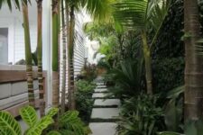 a gorgeous tropical side yard with pavers, greenery and lots of tropical plants and a living wall is a lovely and vibrant space