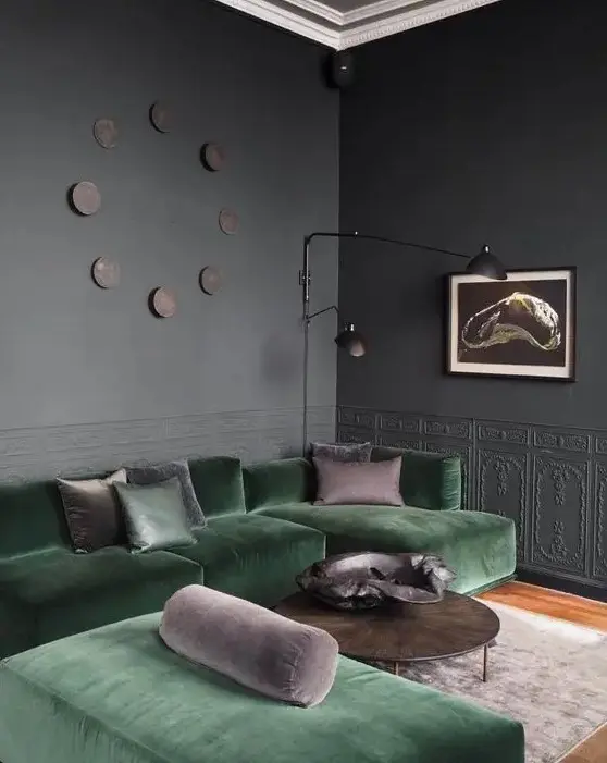 a graphite grey living room with molding, a green sectional and a daybed, some taupe pillows, a coffee table and black lamps