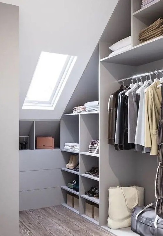 a grey attic closet with open storage compartments, drawers and railings plus a skylight for more natural light