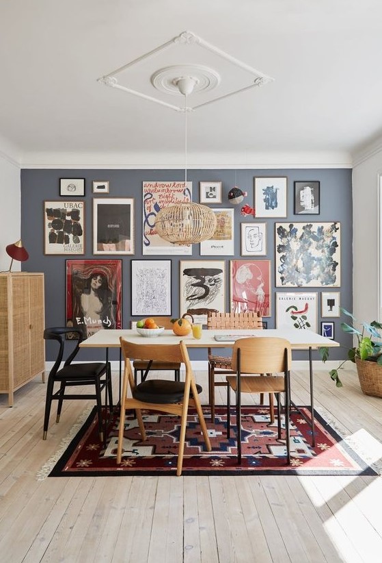 a large and bold free form gallery wall with thin frames and colorful art, mostly abstract, takes over the whole dining space