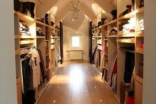 a large attic closet with open shelves and racks, rails and dressers can accomodate a lot of things, and built-in and pendant lights help to find everything you need