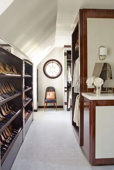 a large attic closet with open shelves and railings, with a round window and a chair and some lovely decor is all cool