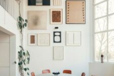 a large gallery wall with hin white, black and blonde wood frames and black, white and terracotta artworks