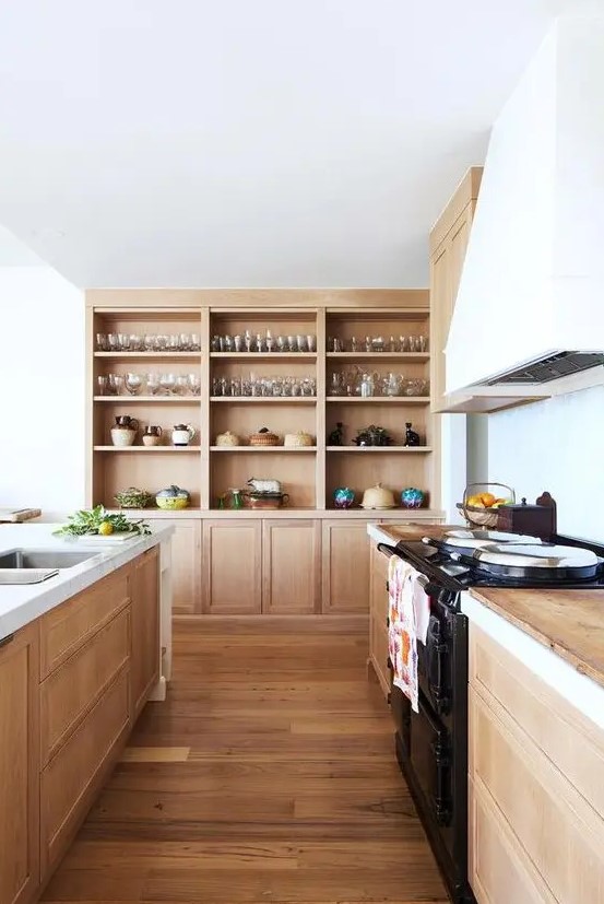 a light-stained wooden kitchen with wooden countertops, built-in wooden storage units and a white hood is very welcoming