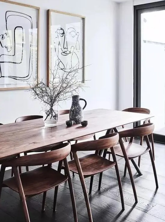 a lovely mid-century modern dining space with a stained table and chairs, a mini graphic gallery wall and a glazed wall