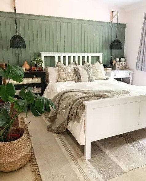 a lovely modern bedroom with a green shiplap wall, a white bed with neutral bedding, mismatching nightstands and black sconces