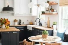a lovely modern country kitchen with white and navy cabinets, butcherblock countertops, pendant lamps and black fixtures