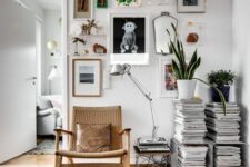 a lovely nook with an eclectic gallery wall, a magazine stacj, a woven chair, a table lamp and some potted greenery
