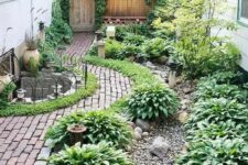 a lush green side yard with a lot of plants, brick paths, gravel and potted plants, too, is a very cozy and lovely space