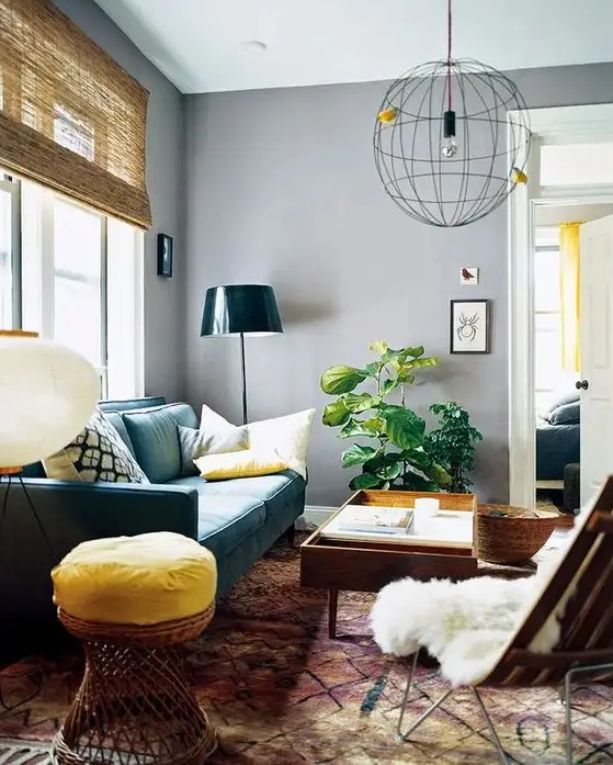 a mid-century modern living room with grey walls, a green sofa, some stained furniture, a bold stool, a sphere pendant lamp and a potted plant