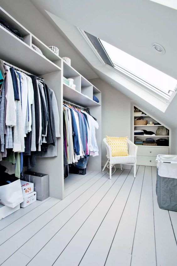 a modern attic closet with a skylight, open storage compartments and railings, built-in shelves and drawers