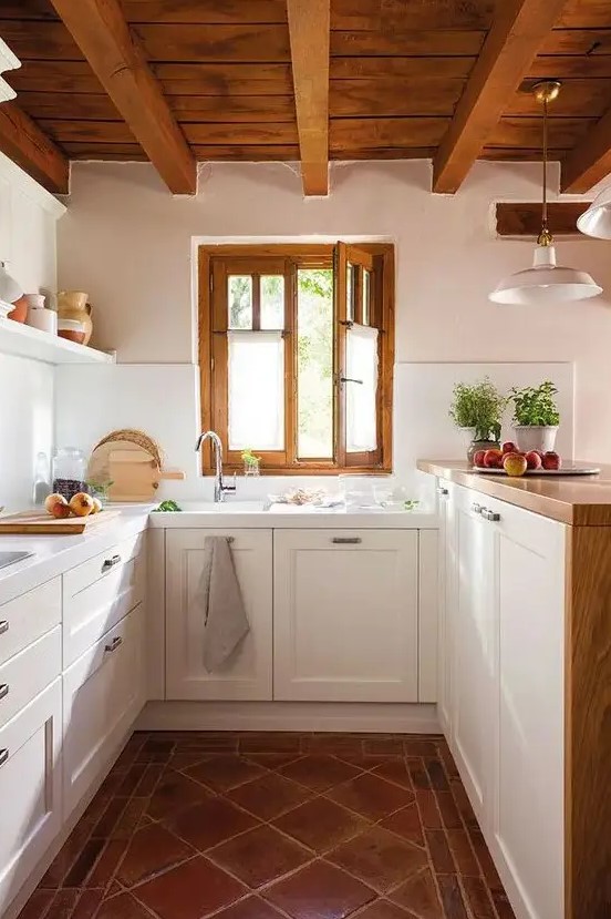 a modern country kitchen with a tiled floor, white cabinets and a raised butcherblock countertops, a wooden ceiling with beams and frames on the window