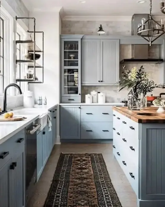 a modern country kitchen with light grey cabinets, butcherblock, white countertops, black fixtures and a vintage metal lamp