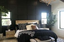 a modern farmhouse bedroom with a black paneled wall, a bed with black and white bedding, nigthstands, a bench and a geo lamp
