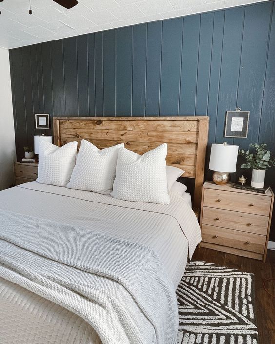 a modern farmhouse bedroom with a blue shiplap wall, a stained bed and nightstands, neutral bedding and table lamps