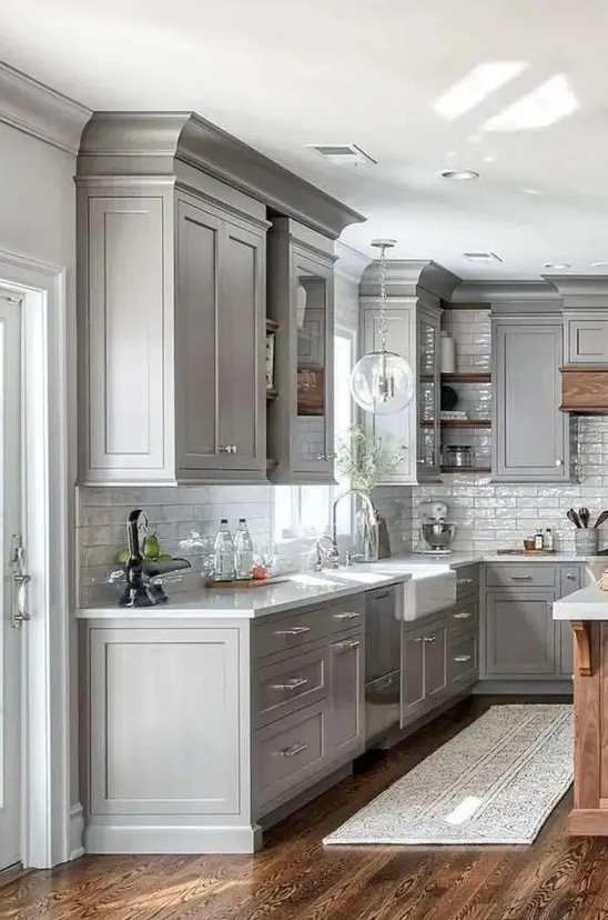 a modern farmhouse grey kitchen with white stone countertops and a white subway tile backsplash, with neutral fixtures is chic