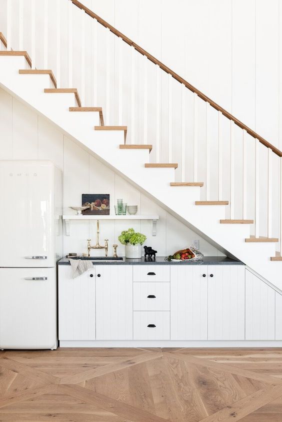 a modern farmhouse kitchen placed under the stairs, with an open shelf and some appliances won't take much floor space