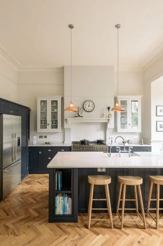 a modern farmhouse kitchen with white and graphite grey cabinets, white stone countertops, pendant lamps and wooden stools