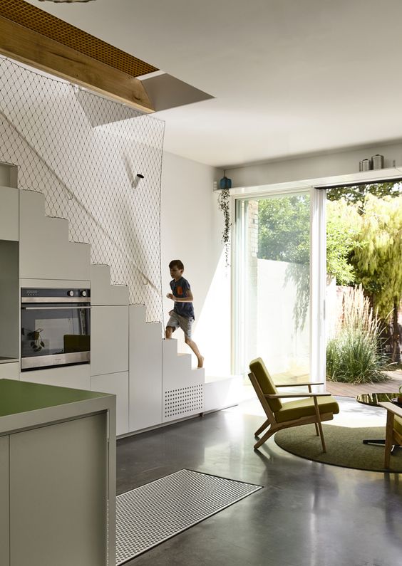 a modern kitchen with a staircase that hides storage compartments, green cabinets is a cool idea for a modern space