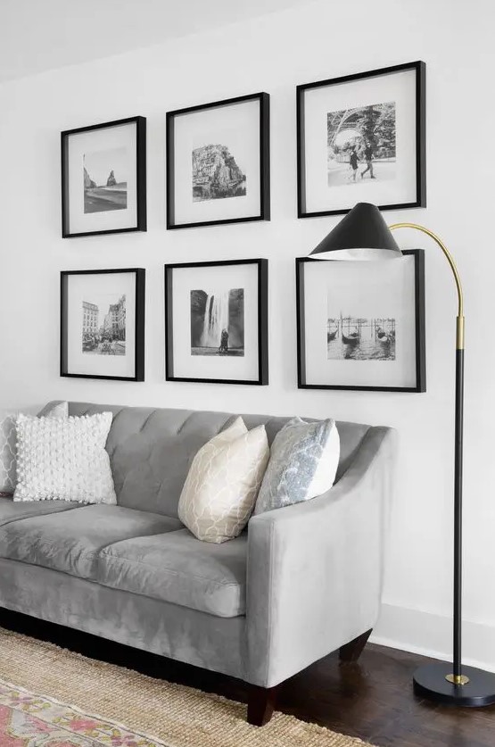 a modern living room with a grid gallery wall, a grey sofa with printed pillows and a black floor lamp