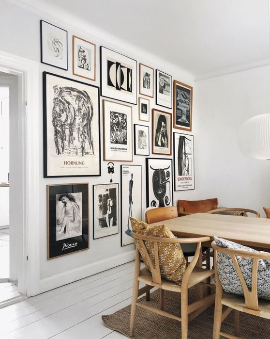 a monochromatic gallery wall with thin black and blonde wood frames and black and white artworks is a stylish idea
