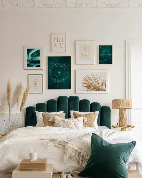 a neutral and forest green bedroom with a bed with an upholstered headboard, a bold gallery wall, a wooden lamp and pampas grass
