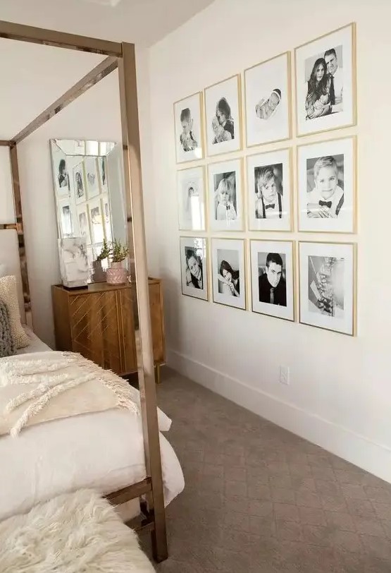 a neutral bedroom with stained furniture, a canopy bed with neutral bedding, a grid gallery wall with gold frames is lovely