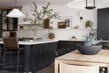 a refined modern farmhouse kitchen with black lower cabinets and a kitchen island, an open shelf with decor and pendant lamps
